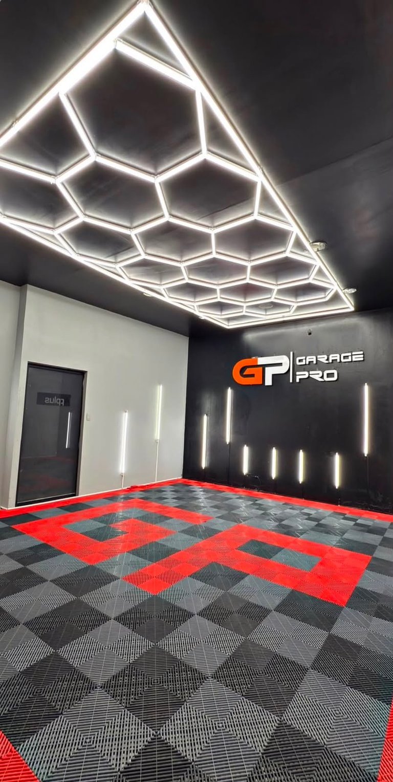 Modern garage interior with hexagonal neon ceiling lights, red and black checkered flooring, and GP Garage Pro branding on wall