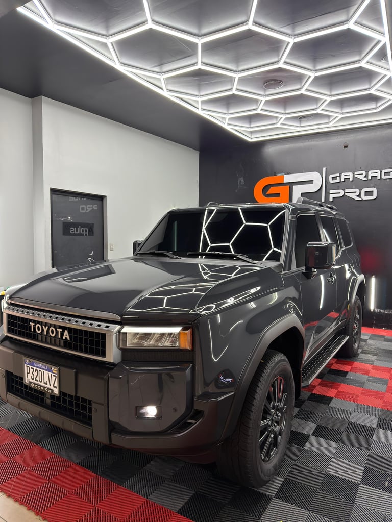 Black Toyota pickup truck in modern garage with hexagonal ceiling lights and Garage Pro signage